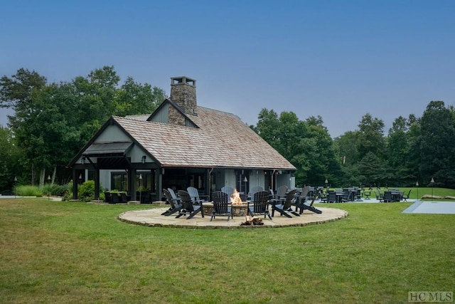 back of house with a yard, a patio, and an outdoor fire pit