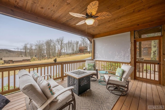 wooden deck with ceiling fan and an outdoor living space with a fire pit