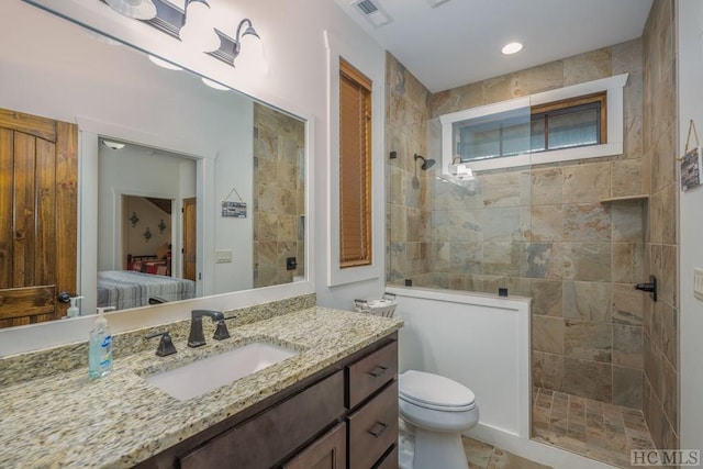 bathroom with a tile shower, vanity, and toilet