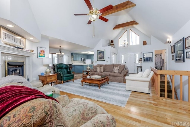 living room featuring high vaulted ceiling, beam ceiling, ceiling fan with notable chandelier, and light hardwood / wood-style floors