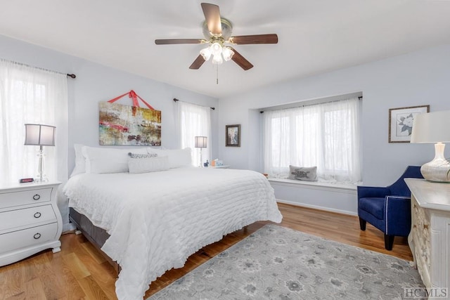 bedroom with ceiling fan, multiple windows, and light wood-type flooring