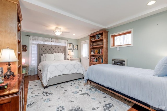 bedroom with ceiling fan, heating unit, and light hardwood / wood-style flooring