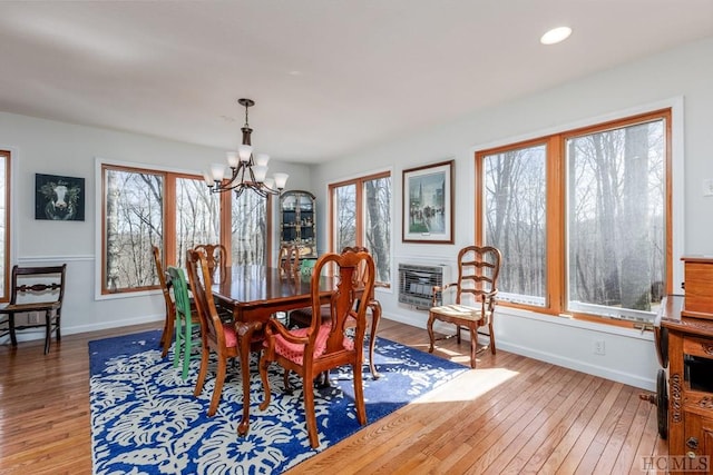 dining area with heating unit, hardwood / wood-style floors, a wealth of natural light, and a chandelier