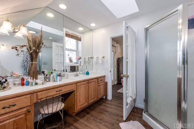 bathroom with vanity, an enclosed shower, wood-type flooring, and a skylight