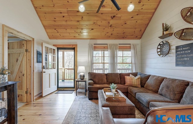 living area featuring light wood-style floors, wooden ceiling, high vaulted ceiling, and wooden walls