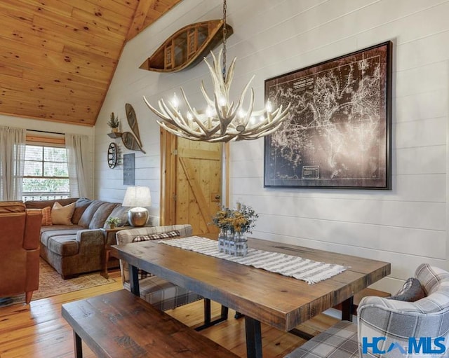 dining area featuring a barn door, a notable chandelier, wood finished floors, wood ceiling, and vaulted ceiling