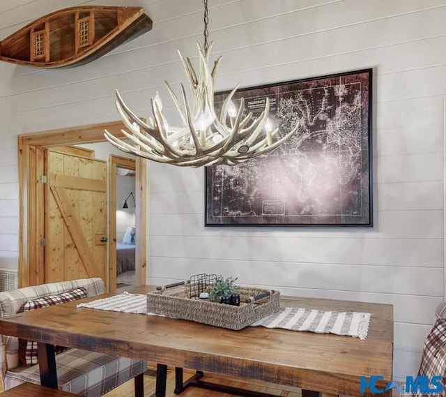 dining room featuring a notable chandelier and wooden walls