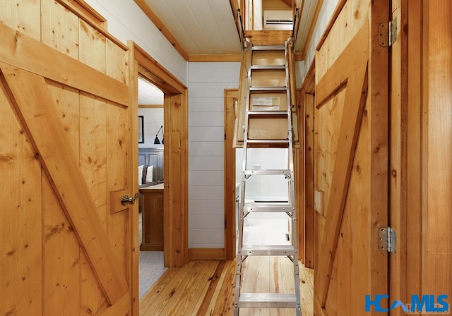 hallway with hardwood / wood-style floors and wooden walls