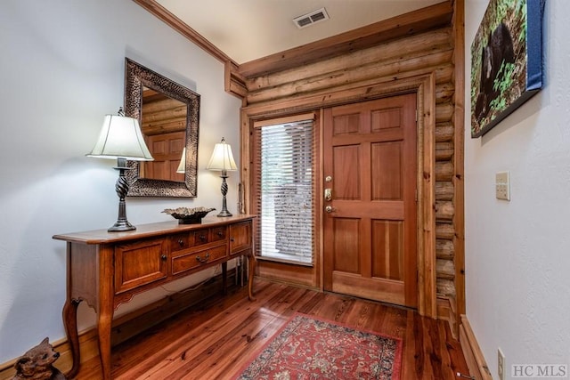 foyer with log walls, ornamental molding, and dark hardwood / wood-style floors