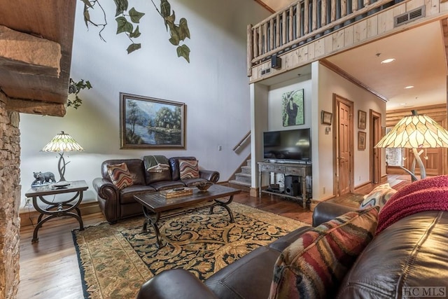 living room with light hardwood / wood-style floors, crown molding, and a towering ceiling