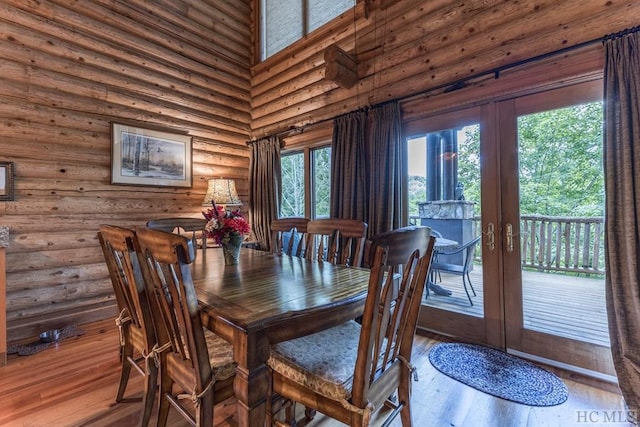 dining room featuring french doors, a towering ceiling, rustic walls, and hardwood / wood-style floors