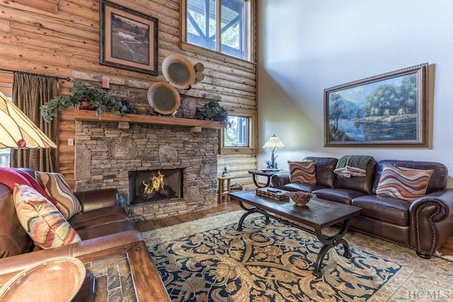 living room featuring a fireplace, a towering ceiling, rustic walls, and light hardwood / wood-style flooring