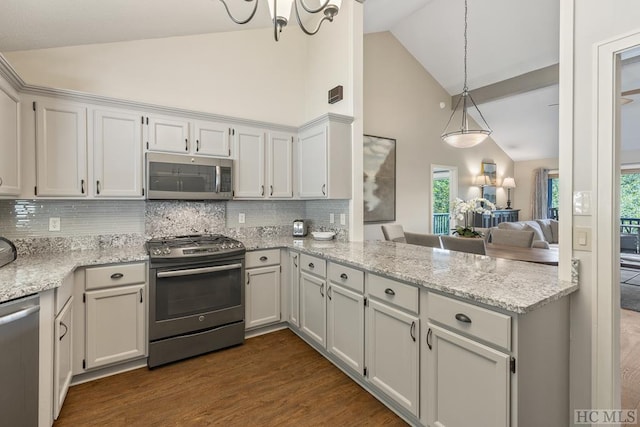 kitchen featuring appliances with stainless steel finishes, white cabinets, backsplash, and decorative light fixtures