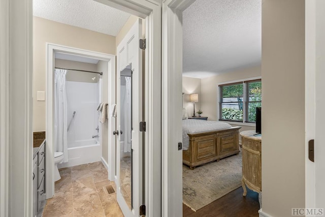 full bathroom with vanity, shower / tub combo, a textured ceiling, and toilet