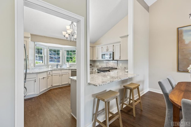 kitchen featuring appliances with stainless steel finishes, white cabinetry, sink, light stone counters, and dark wood-type flooring