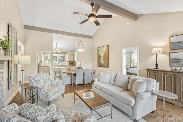 living room featuring beamed ceiling, high vaulted ceiling, ceiling fan with notable chandelier, and light wood-type flooring