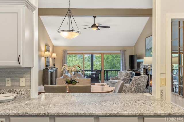 kitchen with white cabinets, light stone countertops, vaulted ceiling, and backsplash