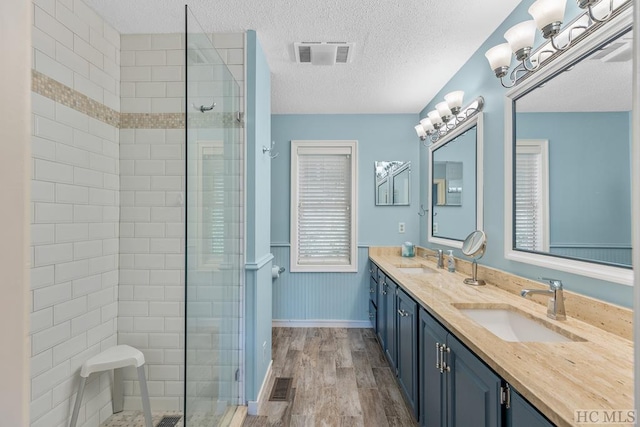 bathroom featuring an enclosed shower, vanity, wood-type flooring, and a textured ceiling