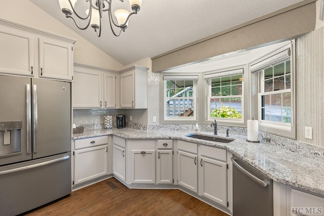 kitchen with sink, vaulted ceiling, stainless steel appliances, and white cabinets