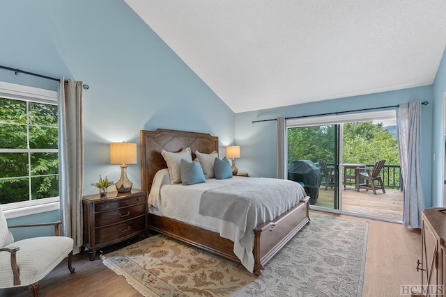 bedroom featuring multiple windows, vaulted ceiling, access to outside, and light hardwood / wood-style floors