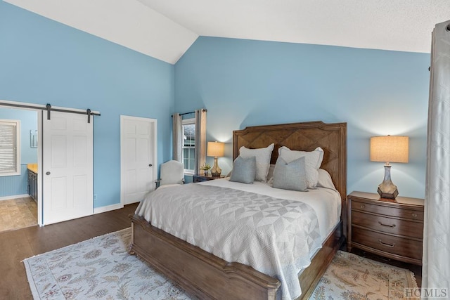 bedroom with a barn door, dark hardwood / wood-style floors, and lofted ceiling