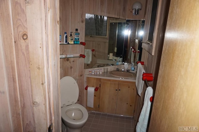 bathroom with tile patterned floors, toilet, vanity, and wooden walls