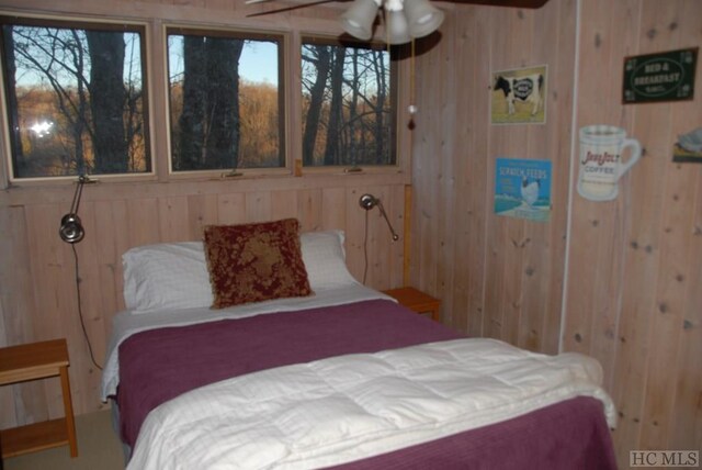 bedroom featuring ceiling fan and wood walls