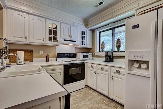 kitchen featuring white appliances, sink, a textured ceiling, and white cabinets