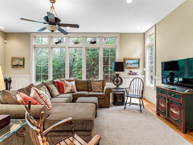 living area featuring a ceiling fan, wainscoting, and wood finished floors