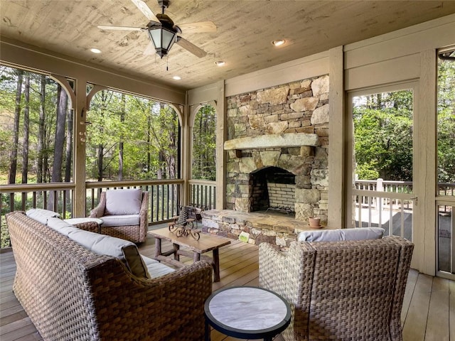 sunroom with an outdoor living space with a fireplace, ceiling fan, and a wealth of natural light