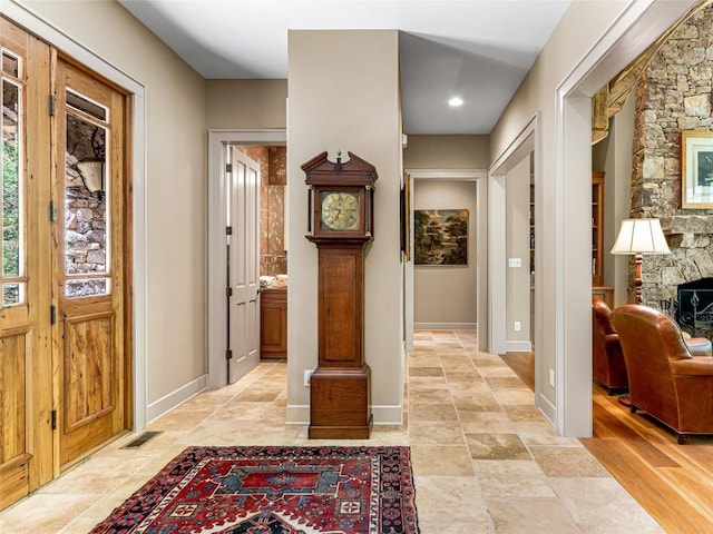 foyer with visible vents, baseboards, stone finish floor, and a fireplace