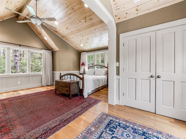 bedroom with wood ceiling, lofted ceiling with beams, a wainscoted wall, and hardwood / wood-style floors