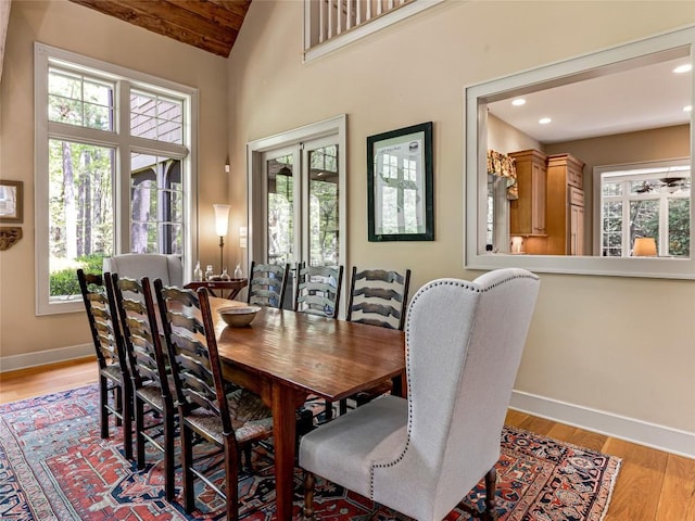 dining room featuring baseboards, recessed lighting, light wood-style floors, and high vaulted ceiling