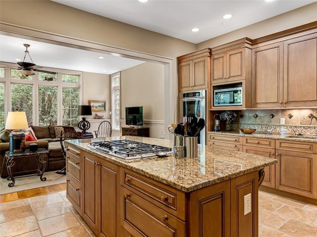 kitchen featuring open floor plan, appliances with stainless steel finishes, a sink, and a center island