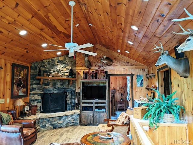 unfurnished living room featuring wooden walls, vaulted ceiling, a stone fireplace, and wooden ceiling