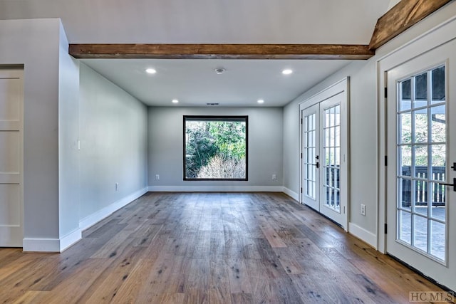 unfurnished room with hardwood / wood-style flooring, beam ceiling, and french doors