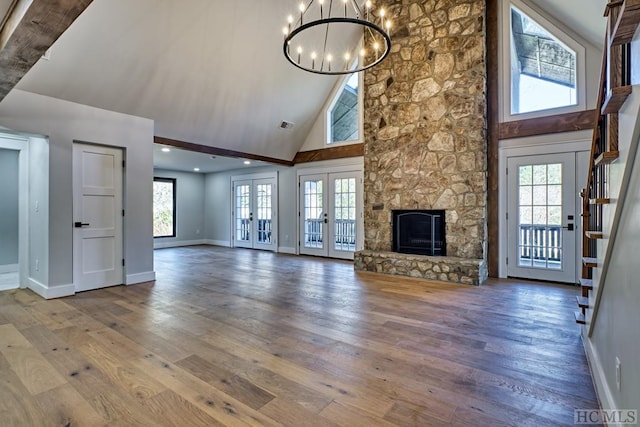 unfurnished living room featuring french doors, plenty of natural light, a fireplace, and hardwood / wood-style floors