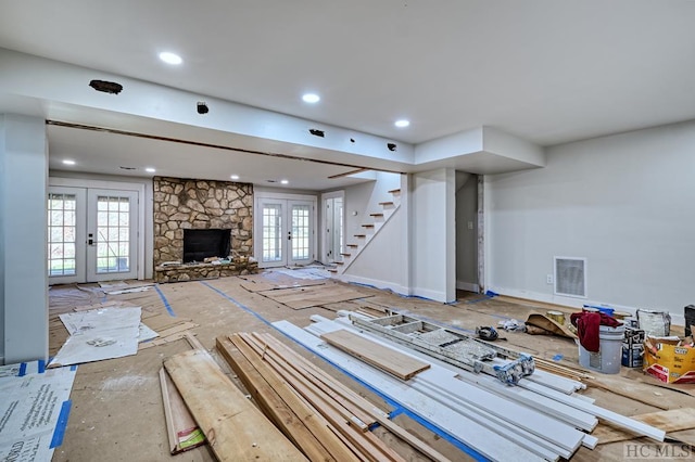 unfurnished living room featuring french doors and a stone fireplace