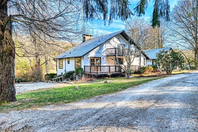 view of front facade with a balcony, a deck, and a front yard