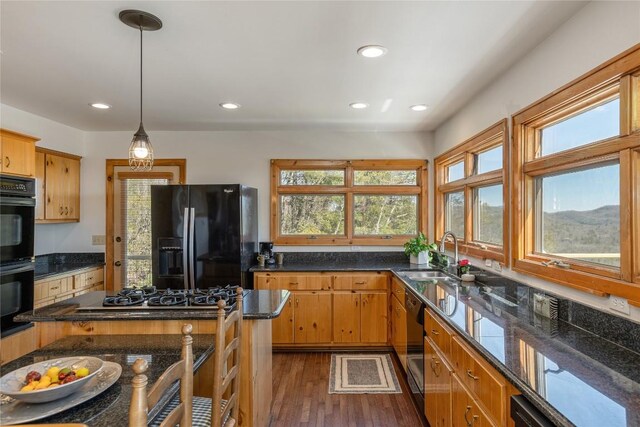 kitchen with dark wood finished floors, recessed lighting, a mountain view, black appliances, and a kitchen island with sink