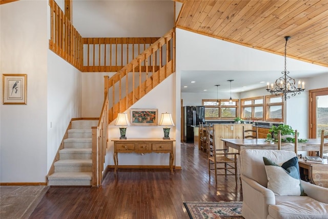 living room with stairway, a notable chandelier, wood ceiling, and dark wood-style flooring