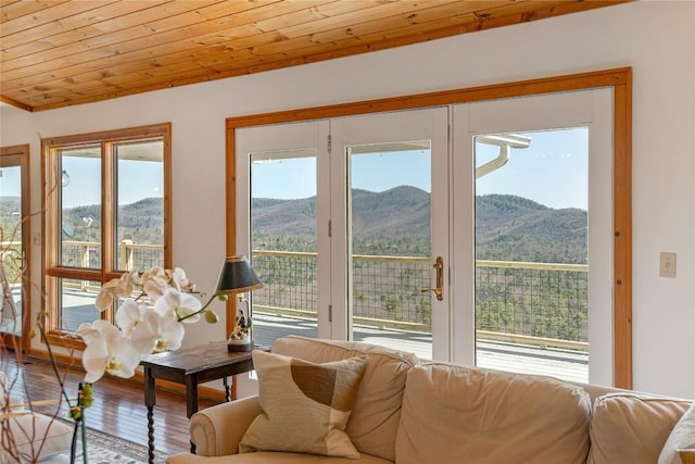 living area with wooden ceiling, a mountain view, and a wealth of natural light