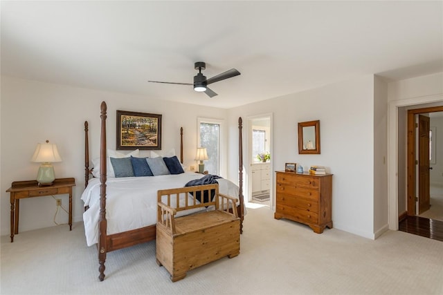 bedroom featuring connected bathroom, baseboards, light colored carpet, and ceiling fan