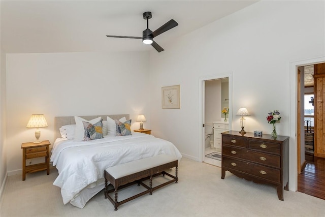 bedroom featuring a ceiling fan, baseboards, light colored carpet, and ensuite bathroom