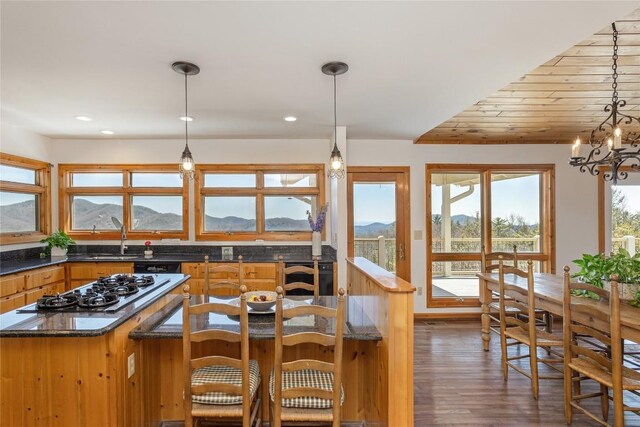 kitchen with a chandelier, a kitchen bar, dark wood-style floors, a mountain view, and a sink