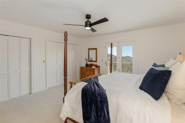 bedroom featuring ceiling fan, multiple closets, light carpet, access to outside, and a mountain view