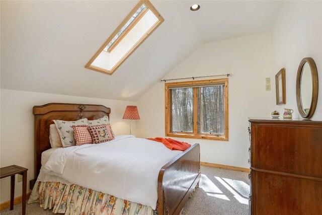 bedroom with baseboards, lofted ceiling with skylight, and light colored carpet