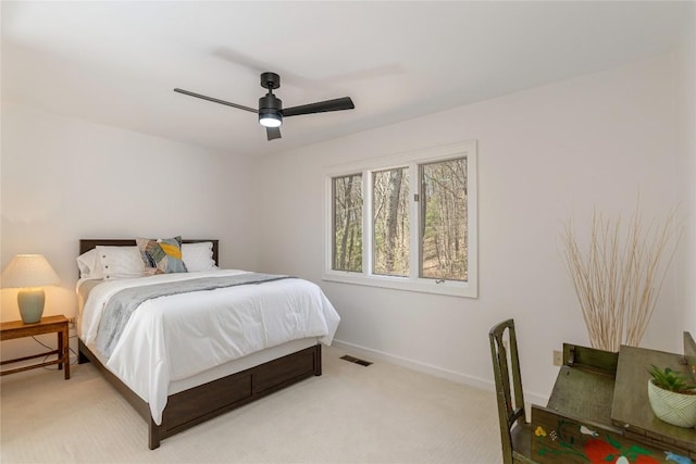 bedroom with visible vents, baseboards, light colored carpet, and a ceiling fan