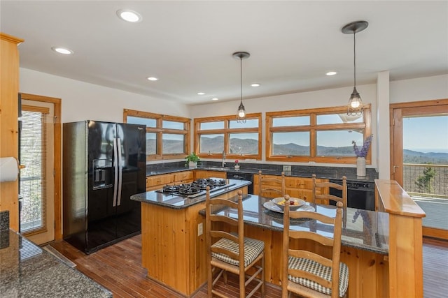 kitchen featuring hanging light fixtures, dark wood-style floors, a mountain view, black appliances, and a sink