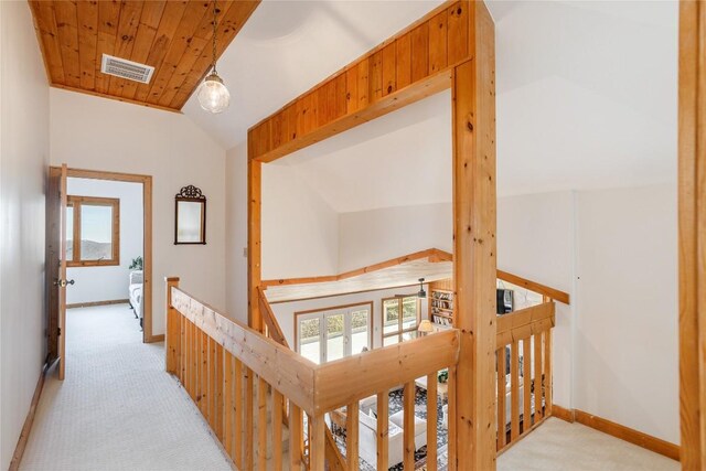 hall featuring vaulted ceiling, an upstairs landing, visible vents, and carpet floors